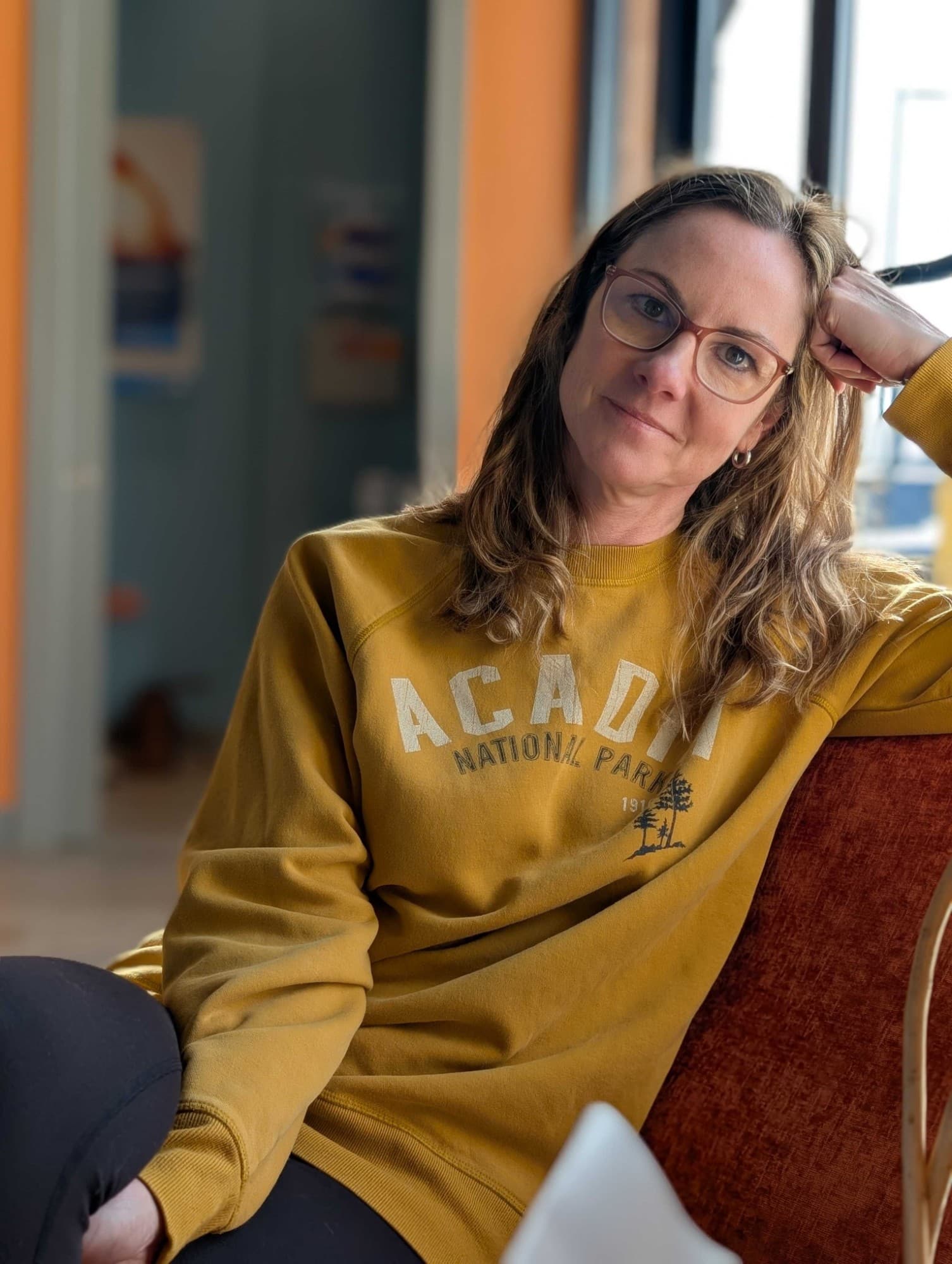 Rebekah P., co-founder of Daili, relaxing on a couch in a warmly lit room