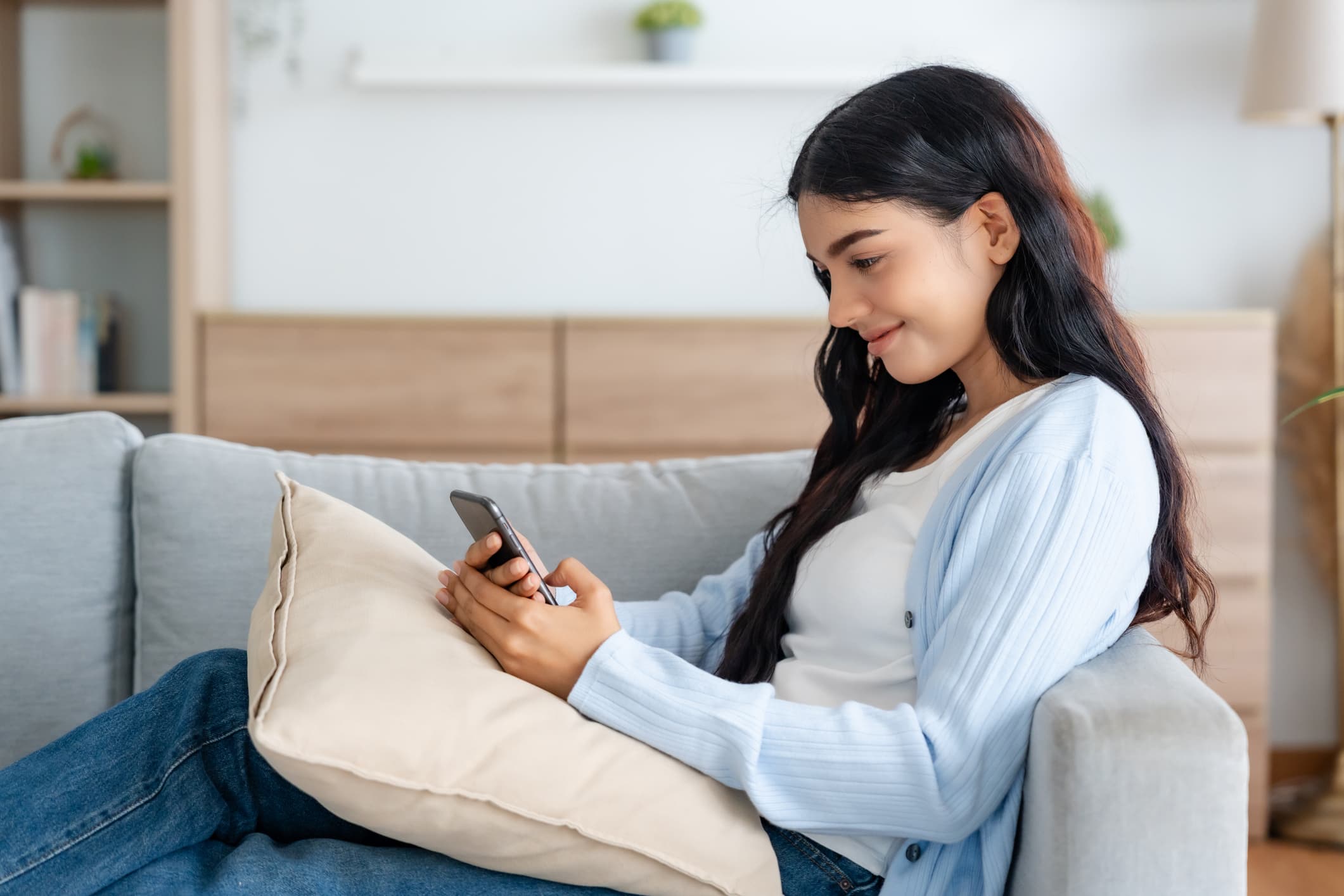 Woman relaxing on couch while checking in on her phone